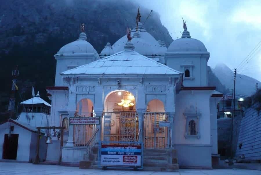 Gangotri Temple illuminated during early morning hours amidst misty Himalayan mountains
