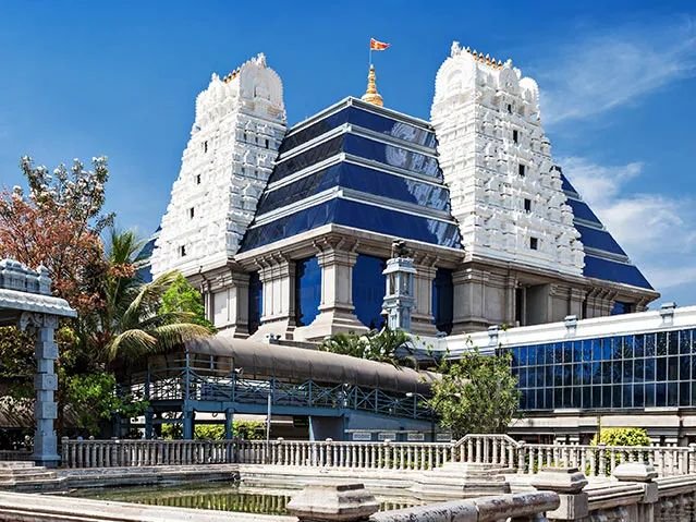 Front view of ISKCON Bangalore temple featuring grand towers, landscaped surroundings, and stunning architectural details.