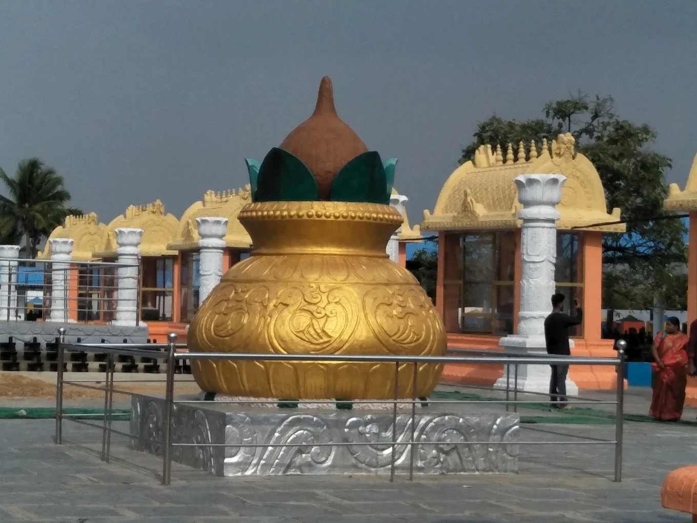 Large golden Kalasha monument inside Kotilingeshwara Temple complex with beautifully designed temple structures in the background.