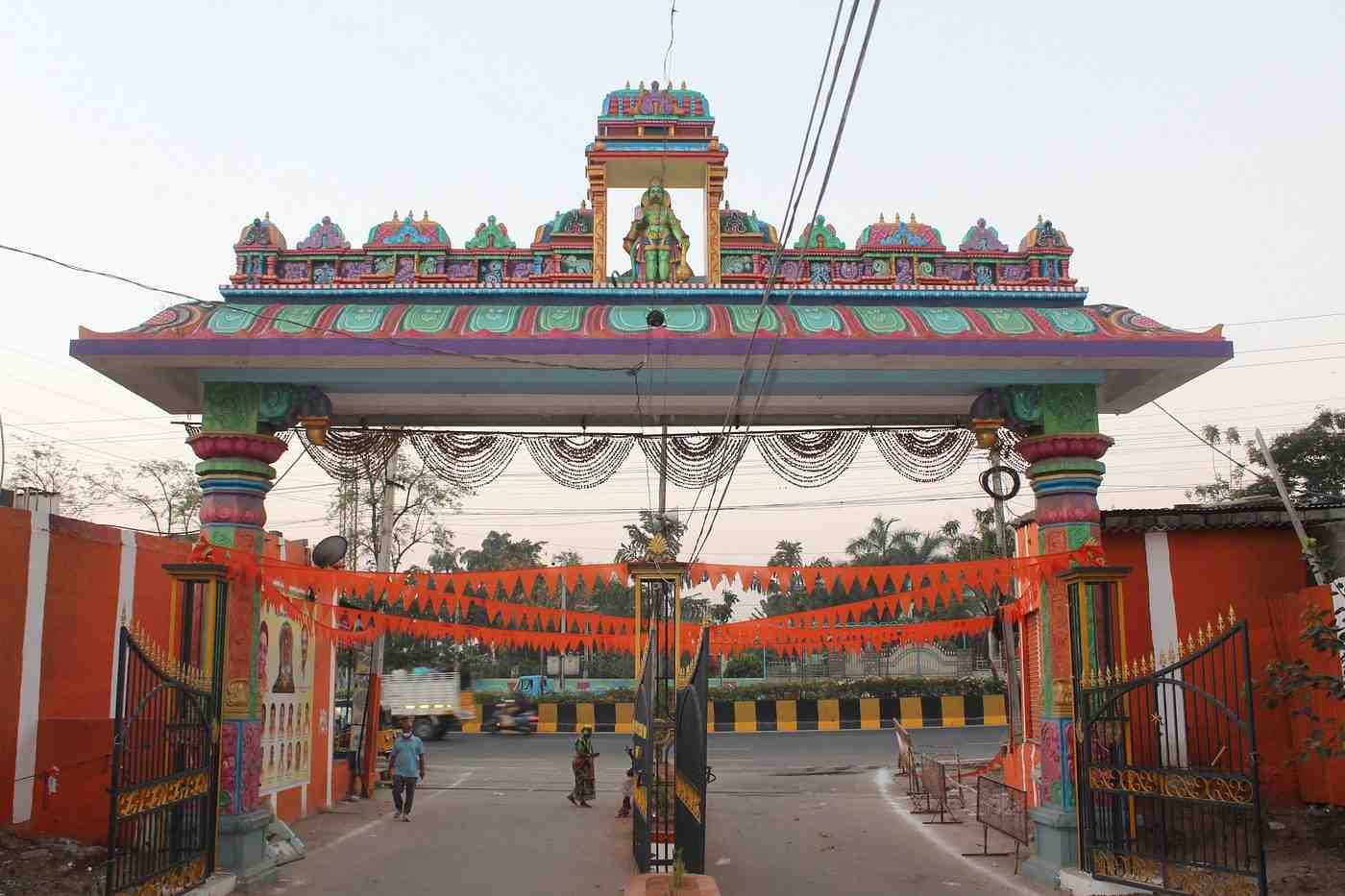 Colorful entrance arch of Karmanghat Hanuman Temple in Hyderabad decorated with traditional Hindu sculptures and festive banners.